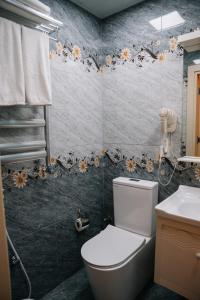 a bathroom with a toilet and flowers on the wall at The Clocktower Hotel in Baku