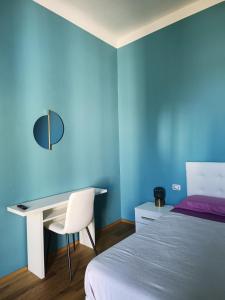 1 dormitorio con paredes azules, escritorio y cama en Amio Apartment - next to M5 Ca Granda, en Milán