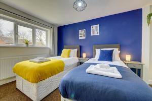 two beds in a room with blue walls and windows at Thurnby Lodge in Leicester