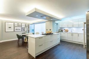 a large kitchen with white cabinets and a table at Stylish Home - Wentworth, Sunningdale Golf Club in Sunninghill