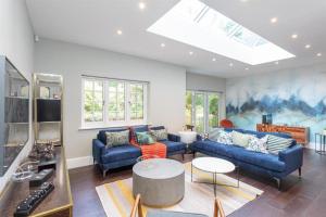 a living room with blue couches and a skylight at Stylish Home - Wentworth, Sunningdale Golf Club in Sunninghill