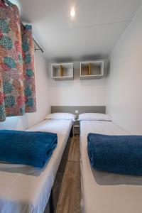 Habitación con 3 camas y almohadas azules. en Albatross Mobile Homes on Camping Playa Brava en Pals