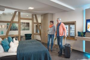 un homme et une femme debout dans une pièce avec une valise dans l'établissement Mühlhäuser Hof- Stadtmauer- Rabe, à Mühlhausen