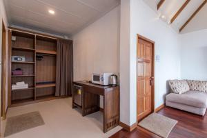 a room with a desk with a microwave and a couch at Twin Bay Resort - SHA Extra Plus in Ko Lanta