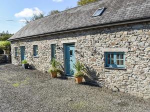 a stone building with a blue door and potted plants at Ysgubor Blaenparc Barn - Uk41030 in Mydroilin