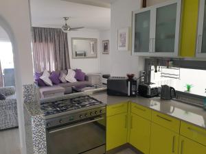a kitchen with yellow cabinets and a living room at The Palms Golf del Sur in San Miguel de Abona