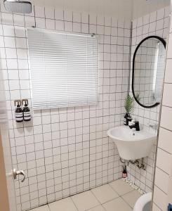 ein weiß gefliestes Bad mit einem Waschbecken und einem Spiegel in der Unterkunft Eeumgil in Daegu