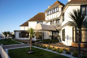 uma casa branca com uma palmeira em frente em The Relais Cooden Beach em Bexhill