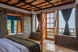 a bedroom with a bed and some windows at THE CEDAR CASTLE in Mukteshwar