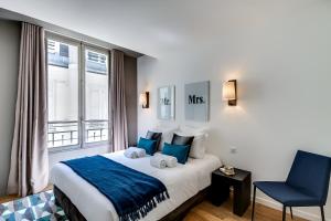Pokój hotelowy z łóżkiem i niebieskim krzesłem w obiekcie Sweett - Parisian Allure w Paryżu