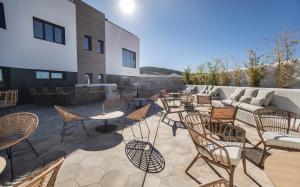 a patio with chairs and tables and a couch at OIKOS APARTAMENTOS TURÍSTICOS in Monesterio