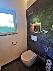 La salle de bains est pourvue de toilettes et d'une fenêtre. dans l'établissement Ferienhaus Gschlössl, à Rauris