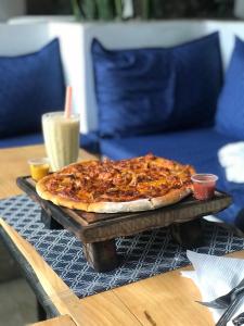 een pizza zittend op een houten blad op een tafel bij Bustown BnB in Arusha