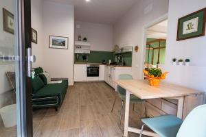 cocina y sala de estar con mesa de madera y sillas verdes en Tenuta Tre Gemme a mare - Suite Salvia, en Pescara
