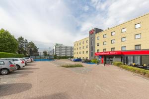 a parking lot with cars parked in front of a building at Thon Hotel Brussels Airport in Diegem