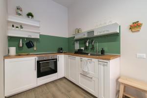 una cocina con armarios blancos y paredes verdes en Tenuta Tre Gemme a mare - Suite Salvia, en Pescara