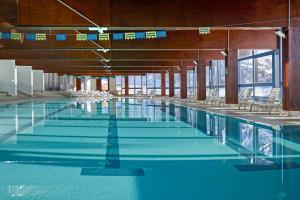 een groot zwembad met stoelen en blauw water bij Blu Hotel Senales Zirm-Cristal in Maso Corto