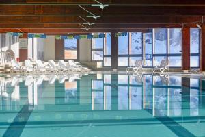 una piscina con sedie bianche e una piscina di Blu Hotel Senales Zirm-Cristal a Maso Corto