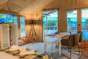 una habitación con mesa y TV en una tienda de campaña en African Safari Canvas Lodge Tent Sea View, en Kranidi