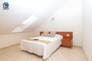 a white bedroom with a bed and a staircase at Residencial Marcomar Casa Azahar in Alcossebre