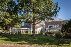 a building with a tree in front of it at Hotel Molenbos Texel in De Cocksdorp