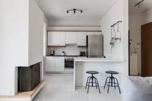 a kitchen with white cabinets and two bar stools at Magnificent 2BR Apartment in Marousi by UPSTREET in Athens