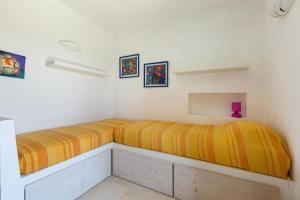 2 camas en una habitación con paredes blancas y rayas amarillas en Villa Elaion by BarbarHouse, en Marina di Pescoluse
