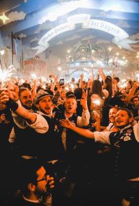 Un groupe de personnes debout dans une foule à une fête dans l'établissement AllYouNeed Oktoberfest camping, à Munich