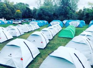 a row of white and green tents in the grass at AllYouNeed Oktoberfest camping in Munich