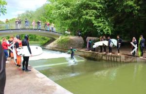 Un gruppo di persone che si trovano su un ponte sopra un fiume di AllYouNeed Oktoberfest camping a Monaco