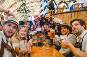 a group of people sitting around a table withints of beer at AllYouNeed Oktoberfest camping in Munich