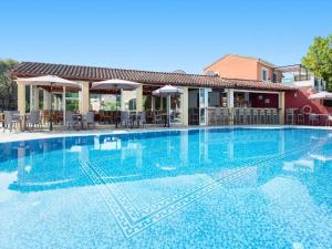 a large blue swimming pool with chairs and umbrellas at Asteraki Poolside Apartment in Acharavi