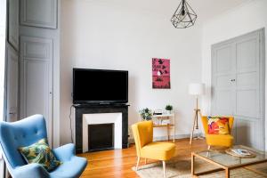 a living room with a fireplace with two chairs and a tv at Esprit Feydeau- 2 chambres en bail mobilité in Nantes