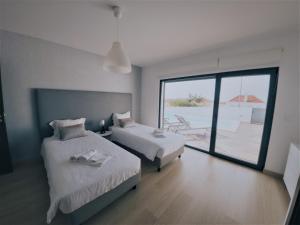 a bedroom with two beds and a view of the ocean at Casa Boa Onda in Lourinhã