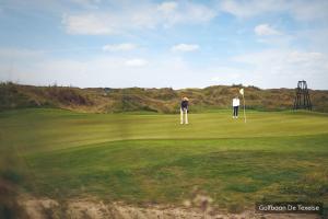 dos personas jugando golf en un campo de golf en Hotel Molenbos Texel en De Cocksdorp