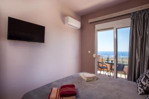 a bedroom with a bed with a television and a balcony at Kalypso Sea View Villa in Koskinou