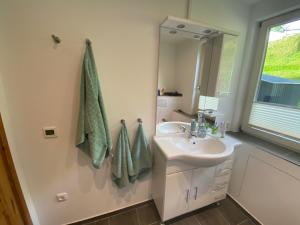 a white bathroom with a sink and a mirror at EXTERTAL-FERIENPARK - Premium-Ferienhaus Sonnenhügel #36 in Extertal