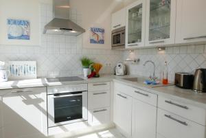 a white kitchen with a sink and a stove at Haus Meeresblick FeWo Strandperle in Baabe