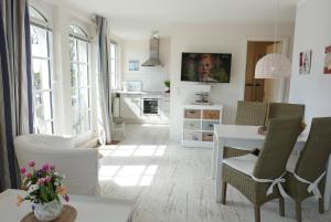 a white living room with a table and chairs at Haus Meeresblick FeWo Strandperle in Baabe