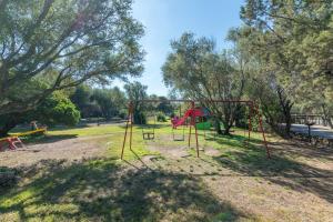 een speeltuin met een schommel in een park bij Casa Emozione With Shared Pool - Happy Rentals in Marinella