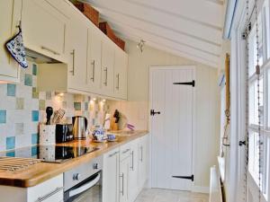 cocina con armarios blancos y encimera en Fern Dale Cottage, en Stockland