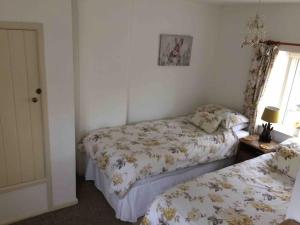 a bedroom with two beds and a window at Fern Dale Cottage in Stockland