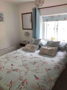 a bedroom with a bed with a floral bedspread and a window at Fern Dale Cottage in Stockland