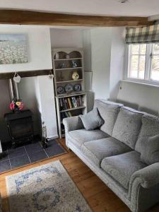 sala de estar con sofá y chimenea en Fern Dale Cottage, en Stockland