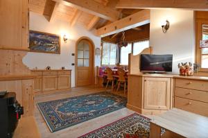 een grote woonkamer met een tv en een keuken bij Mansarda Le Genziane di Fiemme in Cavalese