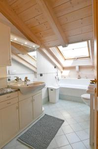 een badkamer met een wastafel, een toilet en een dakraam bij Mansarda Le Genziane di Fiemme in Cavalese