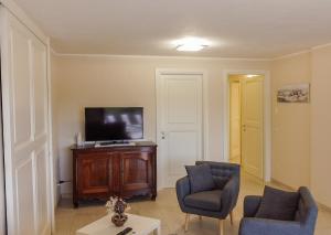 salon z 2 krzesłami i telewizorem z płaskim ekranem w obiekcie Villa Giada w mieście Torre delle Stelle