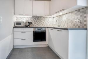 a white kitchen with white cabinets and a microwave at Alpen Living - 1 Stock Ganz in Cadipietra