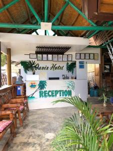 un restaurante con sillas y un cartel que lee la recepción de Pascpect hon en Hotel Oasis Port Barton en San Vicente