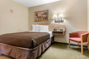 a hotel room with a bed and a chair at Suburban Studios South Bend in South Bend